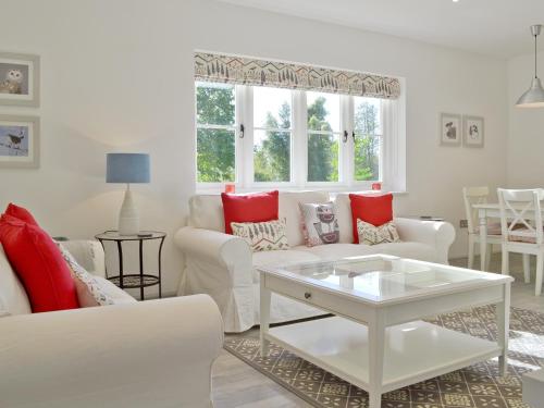 a living room with white furniture and red pillows at Wishing Well Cottage in Mathon