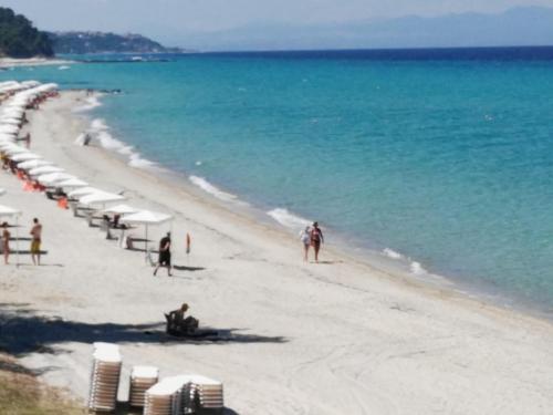 a beach with umbrellas and people on the sand and water at Ariadni -Villas- luxury houses in Kriopigi