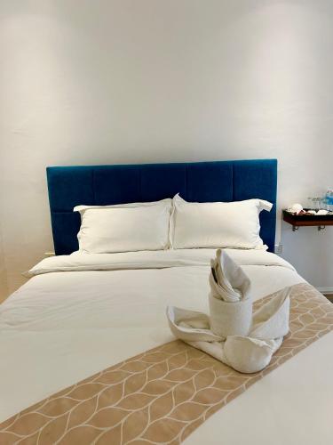 a bed with a blue headboard with a towel on it at Castle View Hotel Samal in Magamomo