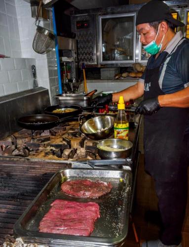 a man preparing meat on a grill in a kitchen at Oceanview Bungalows by EAT in Karon Beach
