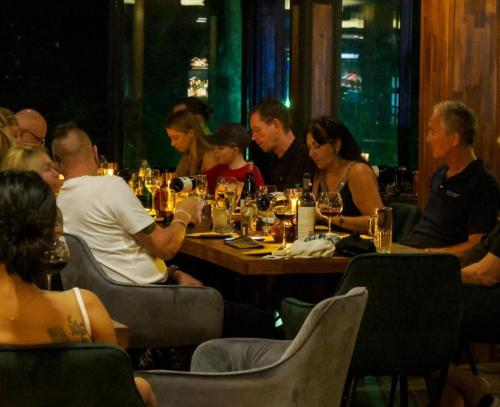 a group of people sitting at a table in a restaurant at Oceanview Bungalows by EAT in Karon Beach