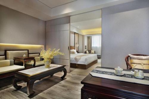 a living room with a couch and a room with two beds at Yuan Culture Hotel Shenzhen World Shajing in Shenzhen