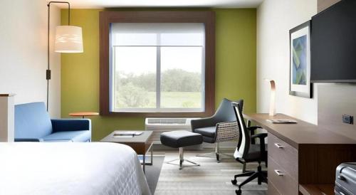a hotel room with a bed and a desk and chairs at Holiday Inn Express & Suite Milroy - Reedsville By IHG in Burnham