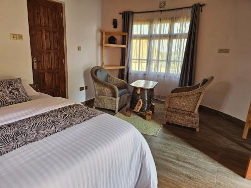 a bedroom with a bed and two chairs and a table at Oiti Boma Lodge Arusha in Arusha