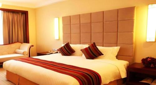 a hotel room with a large bed and a chair at Putian Haiyuan International Hotel in Putian