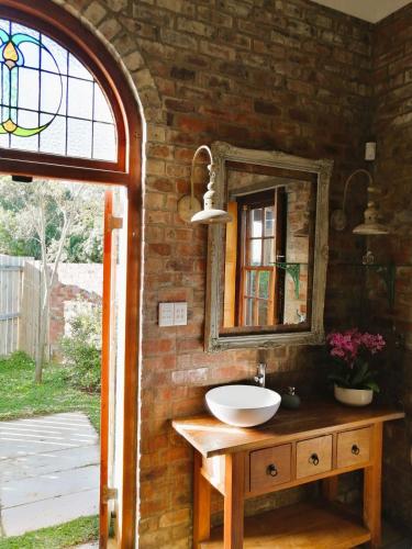 a bathroom with a sink and a mirror on a brick wall at Winelands Manor Vineyard Views in Riebeek-Kasteel