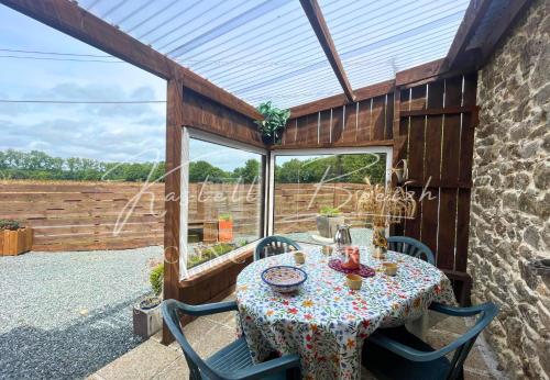 a patio with a table and chairs and a window at Gîte Le Lojou in Le Merzer