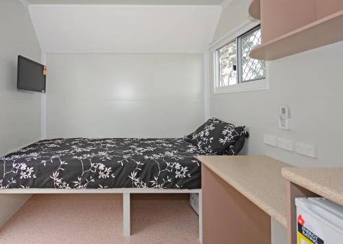 ein kleines Schlafzimmer mit einem Bett mit einer schwarzen und weißen Decke in der Unterkunft AAOK Moondarra Accommodation Village in Mount Isa