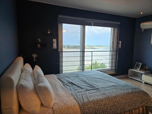 a bedroom with a bed with a large window at Jeju Gaviota Pension in Jeju