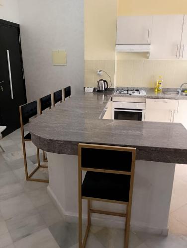 a kitchen with a large counter with chairs in it at Jardin latlantique in Tangier