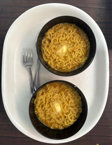 Dos tazones de pasta en un plato con un tenedor en Krishnam Homestay, en Jaipur