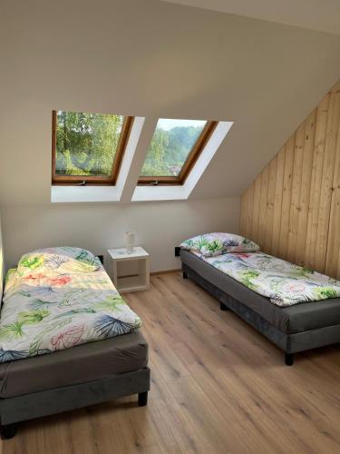 two beds in a room with two windows at Apartamenty Willa NaSkarpie Jacuzzi Sauna Basen in Wisła