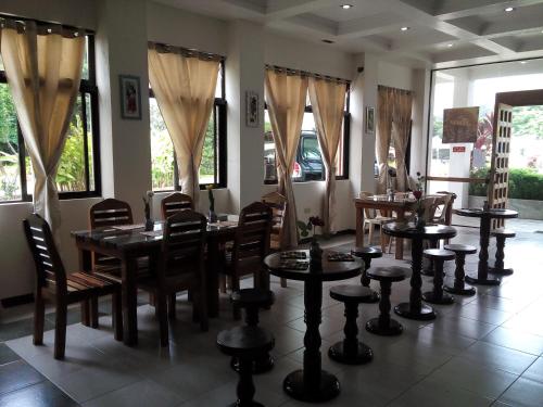 a dining room with tables and chairs and windows at Gazebo Pools and Restaurant in Cabadbaran