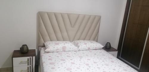 a bedroom with a bed with a white headboard and pillows at appartement proche de l aéroport a Tanger in Tangier