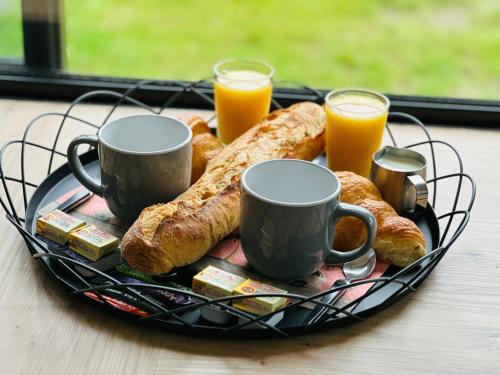 a plate of breakfast food with two cups of orange juice at Le carré long in Neufchâtel-en-Bray