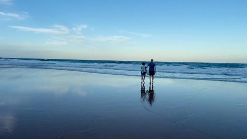 a man and a woman standing on the beach at Coastal Retreat- Beach, Lagoon & Cafes Just Steps from Your Door! in Narrabeen
