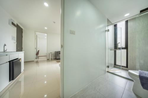 a white bathroom with a toilet and a glass door at SHIN Patara Living Hotel in Bangkok