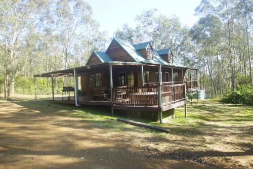 a large house with a wrap around porch at Manzanilla Ridge in Rothbury