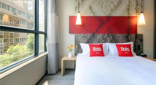 a bedroom with a bed with red pillows and a window at ibis xian North Second Ring Weiyang Rd Hotel in Xi'an