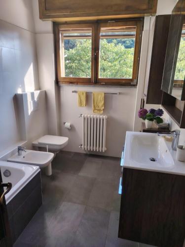 a bathroom with two sinks and a toilet and a window at Villa Bella Porto Valtravaglia in Porto Valtravaglia