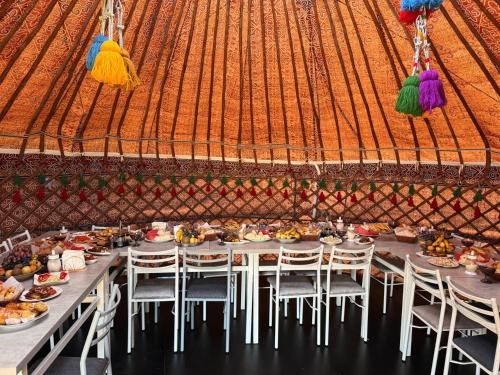 een lange tafel met stoelen en eten in een tent bij One Million Stars Yurt camp in Song-Kul