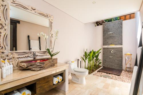 a bathroom with a toilet and a mirror at Villa Can Barca in Seminyak