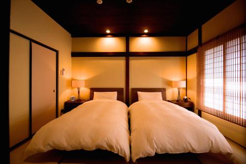 a bedroom with two beds with white pillows at Kazueya in Kanazawa