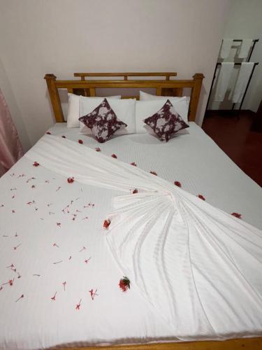 a white bed with red flowers on it at Sena's Cave Villa in Dambulla