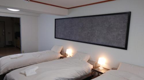 two beds in a room with a large screen on the wall at Newly Reformed! Kawagoe Residence - 上福岡アーバンハイツ in Kamifukuoka