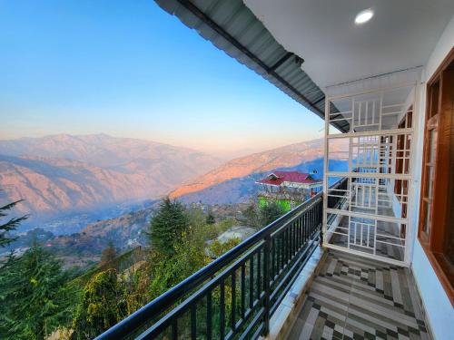 a balcony of a house with a view of mountains at The Halt Narkanda - Rooms and Rooftop Cafe in KumhÄrsain