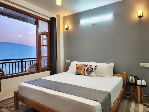 a bedroom with a bed and a large window at The Halt Narkanda - Rooms and Rooftop Cafe in KumhÄrsain