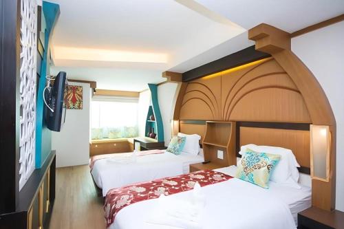 a hotel room with two beds and a tv at Phi Phi Nice Beach Hotel Hip in Phi Phi Don