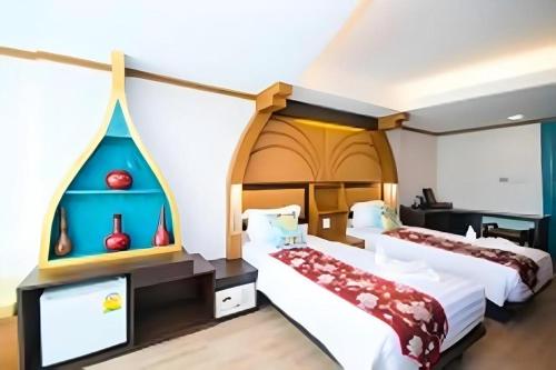 a bedroom with two beds and a tv at Phi Phi Nice Beach Hotel Hip in Phi Phi Don
