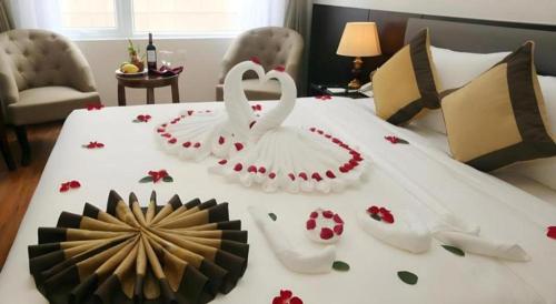 two white swans sitting on a bed with flowers on it at Lenid Hotel Tho Nhuom in Hanoi