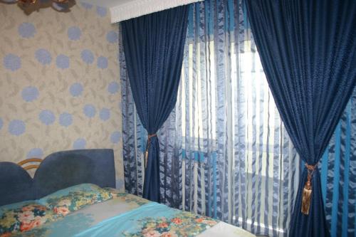 a bedroom with blue curtains and a bed and a window at Salonul Rosu in Bacău