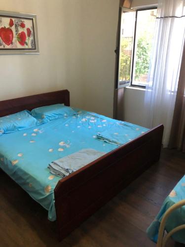 a bedroom with a bed with blue sheets and a window at Apartament Priam in Golem