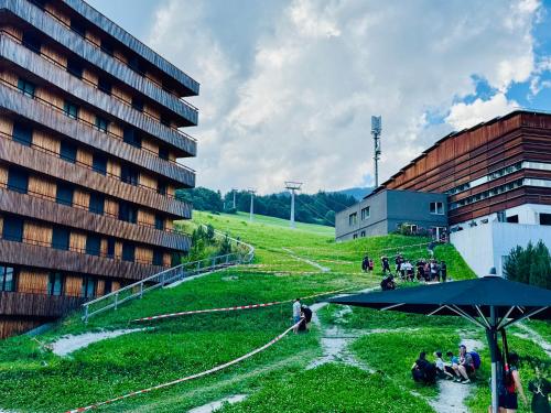 a group of people sitting in the grass next to a building at Sunny Stenna Selva 3-room ski-in ski-out apartment right by the slopes & lifts in Flims
