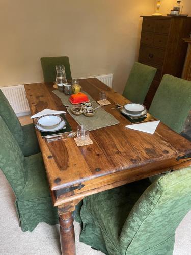 a wooden table with plates and glasses on it at Yew Tree House, Bed & Breakfast in Colchester in Lexden