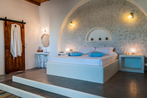 a bedroom with a large white bed with blue pillows at Eiriana Luxury Suites in Plaka Milou