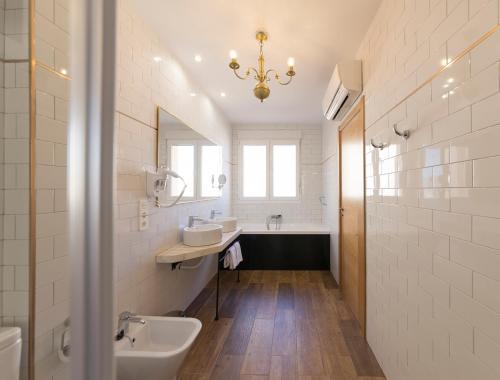 uma casa de banho com 2 lavatórios, uma banheira e um espelho. em Real Segovia by Recordis Hotels em Segóvia