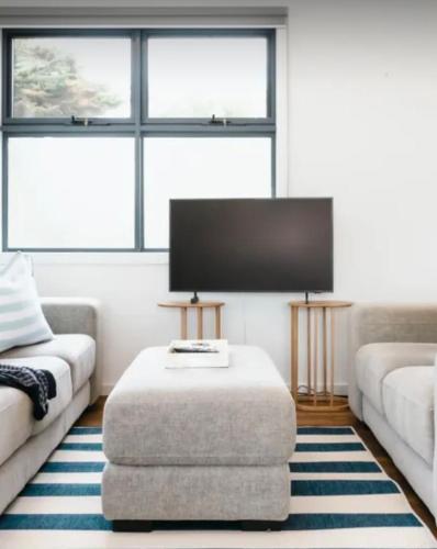 a living room with a couch and a ottoman at Boutique Flinders apartment in Flinders