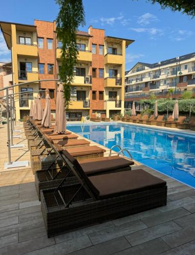 a pool with chairs and umbrellas next to a building at ATOS Srebrno jezero - Villa and Restaurant in Veliko Gradište