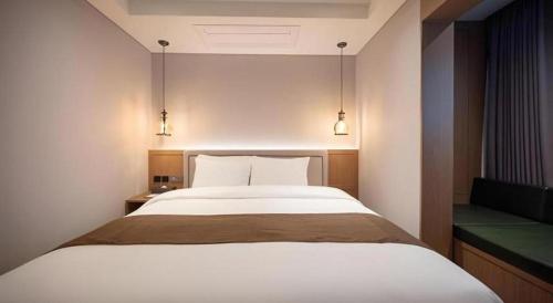 a bedroom with a large bed and two lights at HOTEL D EDITION in Daejeon