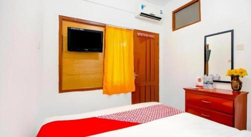 a bedroom with a bed and a dresser and a window at Super OYO 1788 House 24 in Yogyakarta