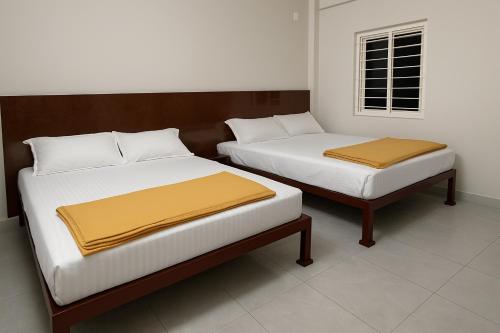 two beds sitting next to each other in a room at Vasavi Palace Residency in Pennāttūr