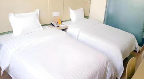 two beds in a hotel room with white sheets at 7 Days Inn Baoding Railway Station in Baoding