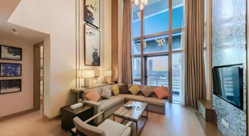 a living room with a couch and a large window at Huafa Executive Apartment Hotel Zhuhai in Zhuhai