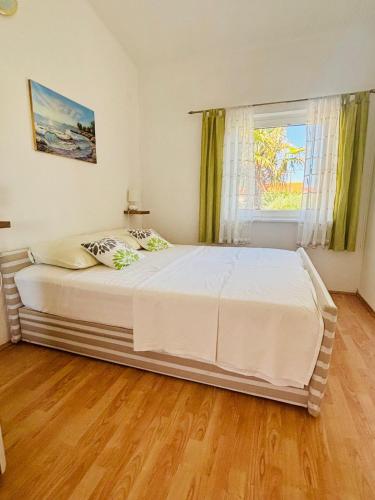 a bedroom with a large white bed and a window at Kaštelina apartments in Vir