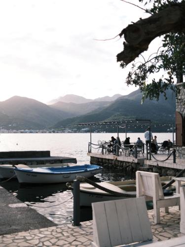 a group of people sitting at a dock with a boat at Kotoro Apartment, Sea View, 60m to Beach, Free Parking in Dobrota