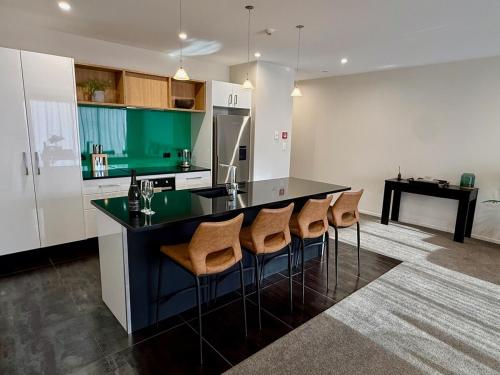 クロムウェルにあるHighlands Oasisのキッチン(黒いカウンター、いくつかのスツール付)